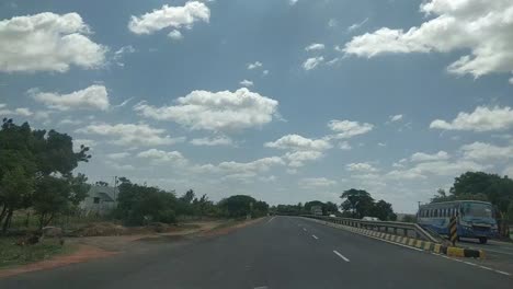 a-time-lapse-video-of-a-vehicle-moving-on-a-highway-with-green-trees-and-bushes-on-wither-side-and-a-blue-sky-with-clouds-above