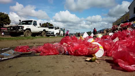 People-walk-past-plastic-garbage-piled-on-street,-slow-motion