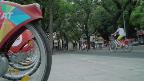 People-ride-Sevici-rental-bicycles-on-bike-lane-in-Seville,-Spain,-Slowmo