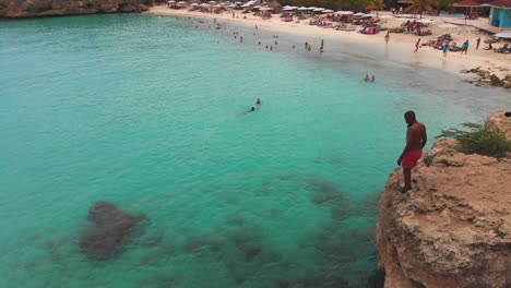 Cliff-jumping-aerial-footage-from-a-mavic-air-at-Grote-Knip-in-the-Dutch-Caribbean,-Curacao