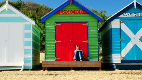 Mädchen-Liest-Buch-In-Brighton-Bathing-Boxes,-Melbourne,-Australien.-Bringon-Bathing-Boxes,-Melbourne