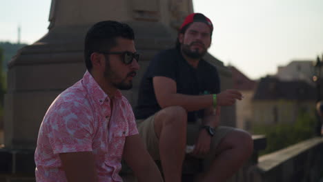 Close-up-view-of-two-young-Latino-guys-smoking-on-the-Charles-Bridge-in-Prague,-Czech-Republic