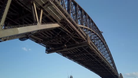 Wunderschönes-Schwenken-Und-Nahaufnahme-Der-Sydney-Harbour-Bridge-Unterhalb-Der-Brücke-Bei-Sonnenuntergang