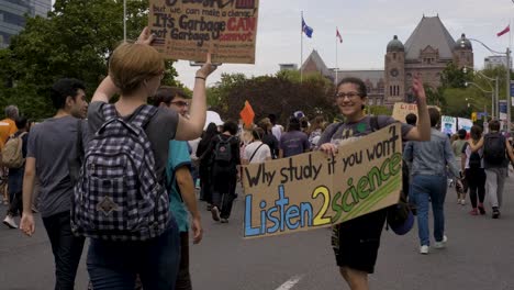 Queenspark,-Toronto,-Canadá---Una-Estudiante-Muestra-Felizmente-Su-Cartel-Mientras-Va-Con-La-Multitud-En-La-Calle---Cámara-Lenta