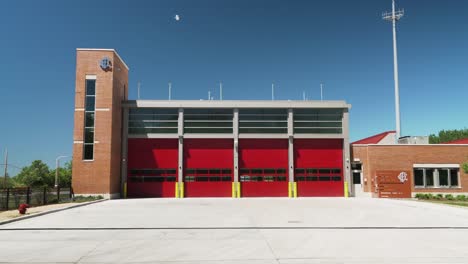 Exterior-De-La-Estación-De-Bomberos-En-Un-Día-Claro-De-Verano-Con-Puertas-De-Garaje-Rojas-Y-Ladrillos