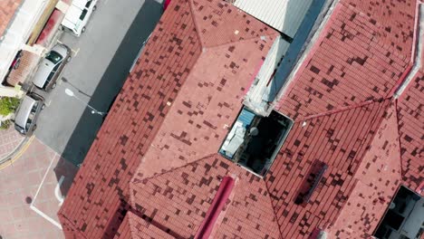 Streets-and-home-roofs-are-seen-from-above-with-parked-cars-and-pedestrians-walking,-Aerial-top-view-flyover-shot