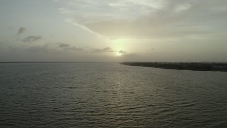 River-flowing-in-Amazon-jungle-at-sunset-in-southern-Suriname,-aerial-pull-away