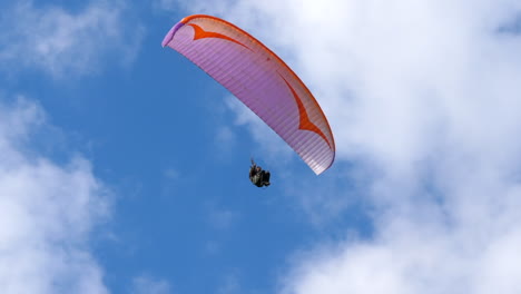 Parapente-Volando-Contra-El-Cielo-Azul-Nublado,-Bandeja-De-Seguimiento-De-ángulo-Bajo