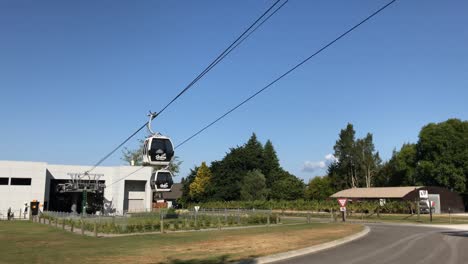 Two-Skyline-gondola-glide-past-each-other-along-the-cables-under-a-clear-blue-sky-in-Rotorua-New-Zealand