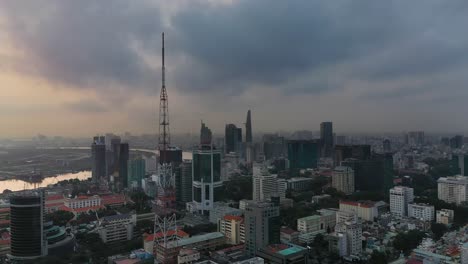 Toma-De-Drones-Temprano-En-La-Mañana-De-La-Ciudad-De-Ho-Chi-Minh-Volando-Hacia-El-Centro-De-La-Ciudad-Con-Vistas-A-Edificios-Clave,-La-Torre-De-Televisión-Y-El-Río-Saigón