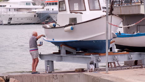 Anciano-Pintando-Un-Barco-En-El-Puerto