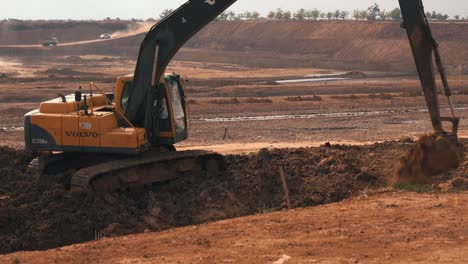 Plano-Medio-De-Una-Excavadora-Excavando-Suelo-En-Un-Gran-Sitio-De-Construcción-En-Asia