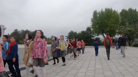 Tracking-shot-of-tourists-walking-near-a-group-of-North-Korean-school-children-and-their-teachers