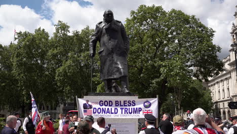 Protestors-at-a-far-right-Hearts-of-Oak-rally-hold-a-banner-in-front-of-the-Winston-Churchill-statue-on-Parliament-Square-that-says,-“God-Bless-Donald-Trump,-two-nations-one-constitution”