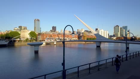 Aerial-rising-shot-of-a-man-walking-in-Puerto-Madero-at-morning,-Buenos-Aires