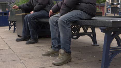 Zwei-Männer-Sitzen-Im-Stadtzentrum-Und-Halten-Sich-Sozial-Distanziert-Auf-Einer-Bank-In-Mittlerer-Aufnahme