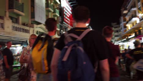 Handheld-scenes-of-the-tourists-are-walking-around-Khao-San-Road-at-night-time-famous-which-each-year-tourists-from-many-countries-came-to-visit-in-Bangkok,-Thailand