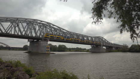 Dos-Trenes-Pasando-Por-El-Puente-Ferroviario-En-Hedel,-Cruzando-El-Río-Maas