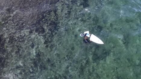 Surfista-Macho-Saliendo-De-Un-Parche-Rocoso-En-La-Playa-De-Balangan-Con-Su-Tabla-Rota-En-Dos-Piezas,-Vista-Aérea-Superior