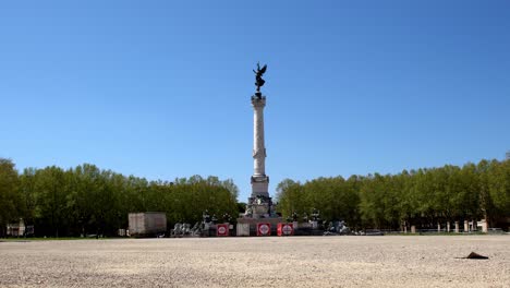 Angel-of-Liberty-Girondins-monument-column-during-the-COVID-19-pandemic-with-commercial-trailer-boxes-below,-Locked-down-shot