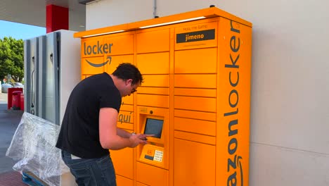 Ein-Mann-Holt-Ein-Paket-Am-Amazon-Hub-Locker-Abholpunkt-In-Spanien-Ab,-Statische-4K-Aufnahme