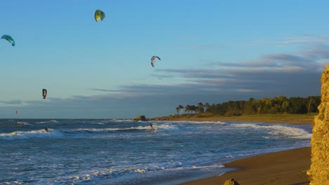 Eine-Gruppe-Von-Leuten,-Die-An-Einem-Sonnigen-Herbsttag-Kitesurfen-Betreiben,-Hohe-Wellen,-Ostsee-Karosta-Strand-In-Liepaja,-Weitwinkelaufnahme