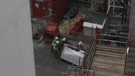 Trabajadores-Que-Cargan-Materiales-En-El-Elevador-Del-Sitio-De-Construcción-En-Millbank