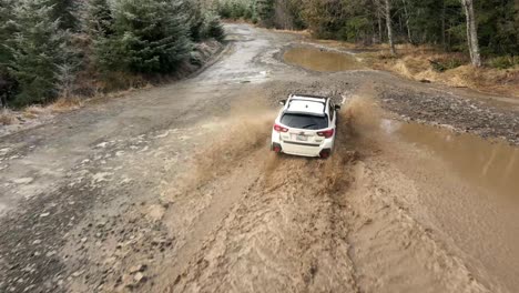 Persiguiendo-Un-Subaru-Crosstrek-A-Través-De-Charcos-De-Lodo-Marrón-Profundo,-Editorial-Aérea-E-Ilustrativa