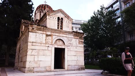 Iglesia-De-La-Virgen-María-Gorgoepekoos-Y-San-Eleuterio-Mientras-Una-Mujer-Se-Aleja-En-El-Centro-De-Atenas,-Grecia