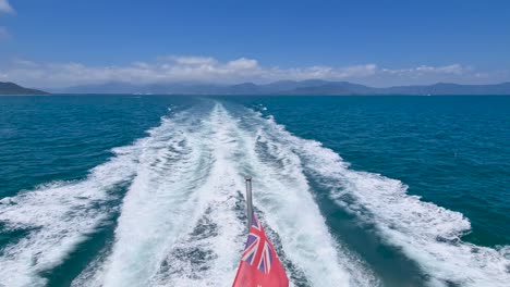 Bandera-Roja-Australiana-Ondeando-Contra-Las-Olas-Desde-Un-Barco-Navegando-Hasta-La-Gran-Barrera-De-Coral