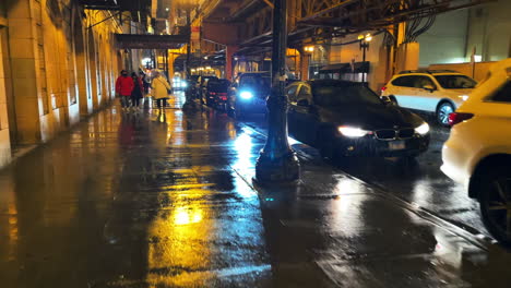 Vista-En-Primera-Persona-De-Una-Calle-Concurrida-En-Chicago-Por-La-Noche-Bajo-La-Lluvia