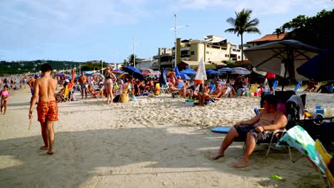 Muñeco-De-Gente-Descansando-Bajo-Las-Sombrillas-Mientras-Los-Niños-Juegan-En-La-Arena-En-Las-Playas-De-Bombas-Y-Bombinhas,-Brasil