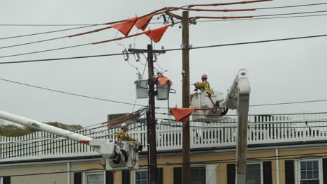 Construction-workers-on-boom-lifts-repairing-power-cables,-California