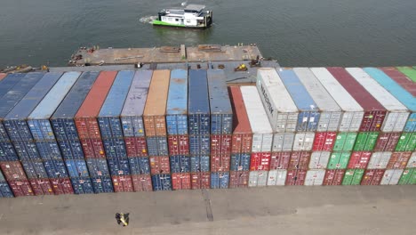 Boat-Sailing-At-Sea-Near-Stack-Of-Freight-Containers-At-Container-Port-Warehouse-In-Dordrecht,-Netherlands