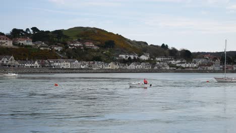 Small-fishing-boat-navigating-seaside-tide-on-fishing-town-waterfront-coastline