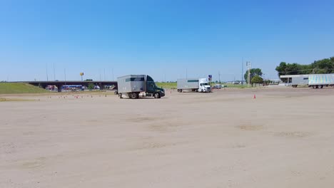 Student-jackknifes-tractor-while-learning-how-to-maneuver-a-semi-tractor-and-trailer-backwards-into-a-parking-spot-in-a-large-empty-lot