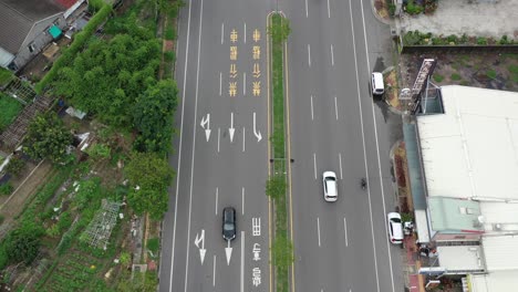 Imágenes-Aéreas-De-Drones-Con-Vista-De-Pájaro-De-La-Carretera-Asfaltada-En-Taiwán,-Drones-Volando-A-Lo-Largo-De-La-Carretera-Recta,-Inclinándose-Hacia-Arriba-Que-Conduce-A-Edificios-Residenciales,-Cielo-Y-Montañas