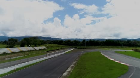 Coche-De-Carreras-Rojo-En-La-Pista-De-Carreras-En-Un-Día-Soleado-Con-Drones