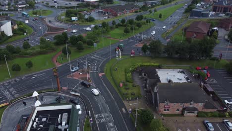 Aerial-view-above-busy-British-shopping-retail-car-park-store-traffic-shops-top-down-orbit-left