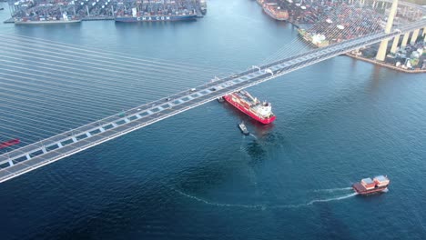 Gran-Buque-Portacontenedores-Que-Sale-De-La-Bahía-De-Hong-Kong-Bajo-El-Puente-De-Los-Canteros,-Vista-Aérea