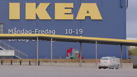 Un-Automóvil-Pasa-Junto-A-Un-Carro-Abandonado-En-Un-Estacionamiento-Vacío-De-Ikea