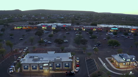 Vista-De-Drones-De-Autos-Alineados-Afuera-De-Una-Cadena-De-Comida-Rápida-En-Un-Valle-Verde-Al-Atardecer