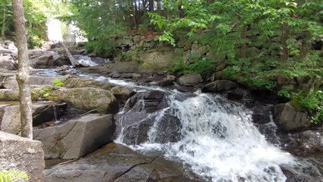 Una-Pequeña-Cascada-Con-Personas-En-El-Fondo-En-Ontario,-Canadá,-Panorámica-De-Tiro-De-Bajada-Ancha-A-Media-A-La-Derecha