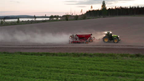 Aéreo---Tractor-Sembrando-Semillas-Al-Anochecer,-Hedemora,-Suecia,-Plano-Amplio-Hacia-Atrás