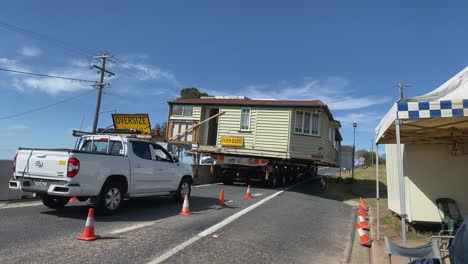 4K-UHD-Panning-view-of-oversize-vehicle-carrying-a-house-on-road-on-a-sunny-day-with-white-clouds-above-at-the-Wallangarra-Covid-border,-Southern-Downs-Region,-Australia