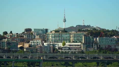 Seoul-Namsan-tower-over-Yongsan-ru-district-urban-skyline,-Daytime-traffic-on-Gangbyeonbuk-ro-expressway-in-Autumn-static-copy-space