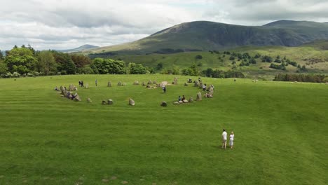 Sitio-Antiguo-Del-Círculo-De-Piedra-De-Castlerigg-Vista-Aérea-Ascendente-Que-Muestra-Montañas-En-El-Fondo-Y-Gente-Divirtiéndose,-Durante-El-Verano-Keswick-Cumbria-Reino-Unido