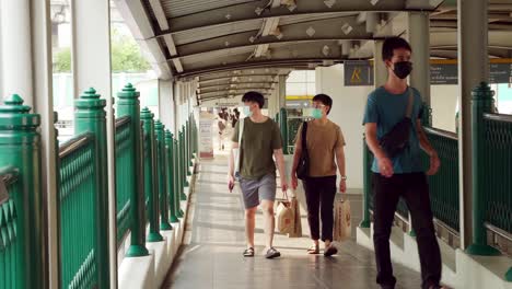 People-wearing-masks-walk-on-a-bridge-connecting-the-central-mass-transit-system-during-the-COVID-19-pandemic