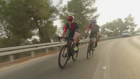 two-road-cycelist-professionals-riding-in-the-forest's-empty-road