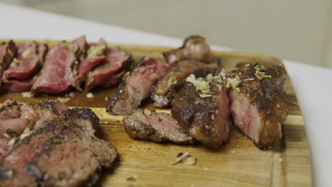 Slices-of-freshly-grilled-beef-steak-layed-out-on-wooden-cutting-board